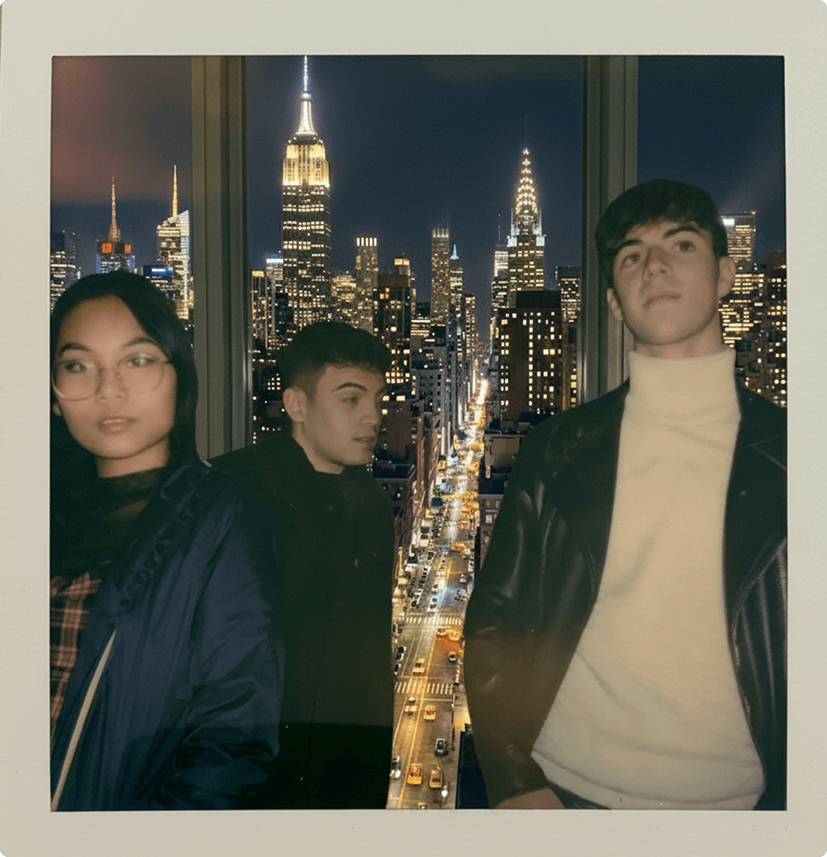 Three friends in front of the New York City skyline at night